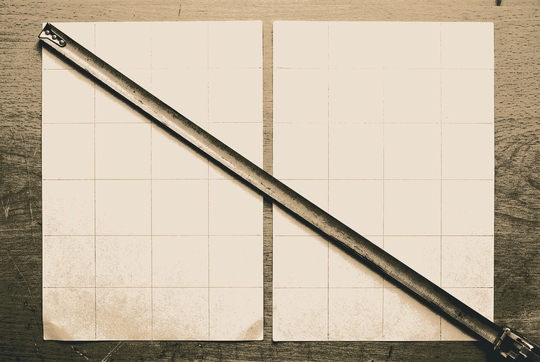 A steel tape measure pulled taut in a diagonal line across two blank calendar sheets lying side by side on a desk.